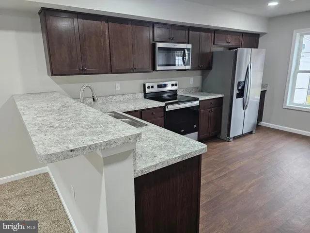 a kitchen with stainless steel appliances granite countertop a refrigerator a stove a sink and a microwave