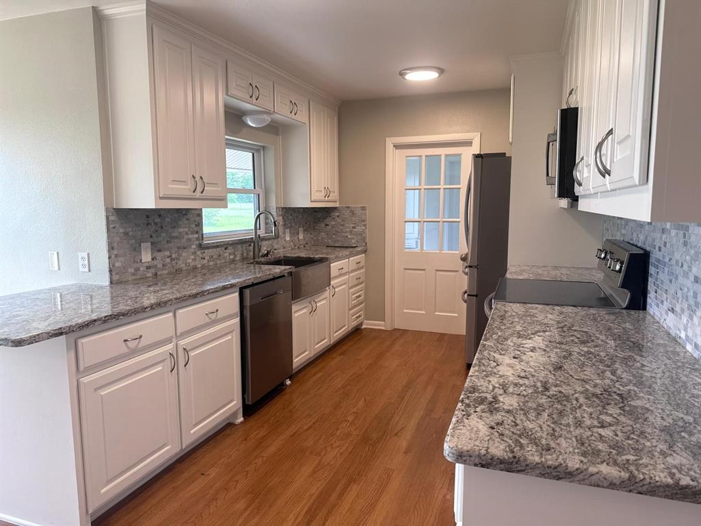626 Stiff Chapel Road Gunter, TX 75058 - Photo 12 of 40 a kitchen with granite countertop wooden cabinets and white appliances