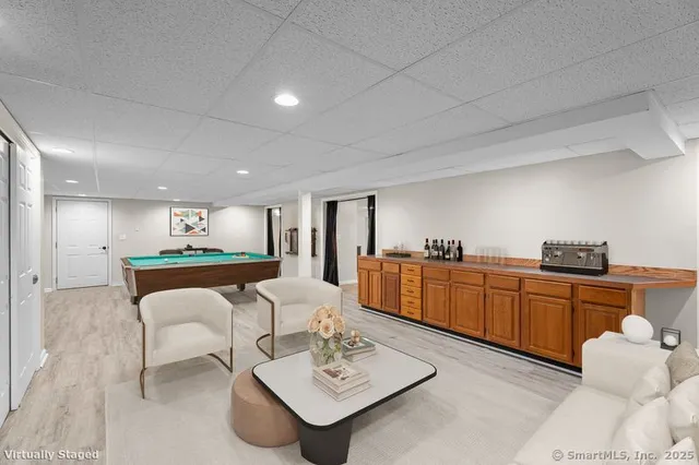 a living room with furniture a kitchen view and a wooden floor