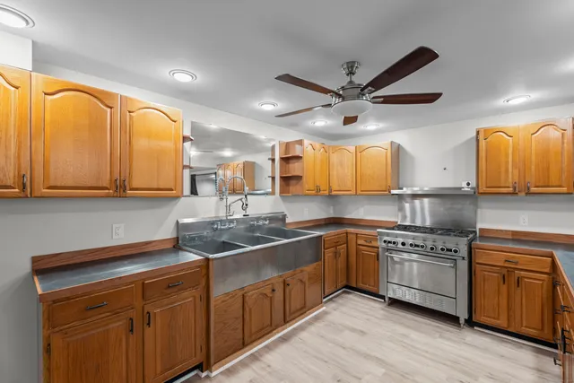 a kitchen with stainless steel appliances granite countertop a sink a stove cabinets and wooden floor