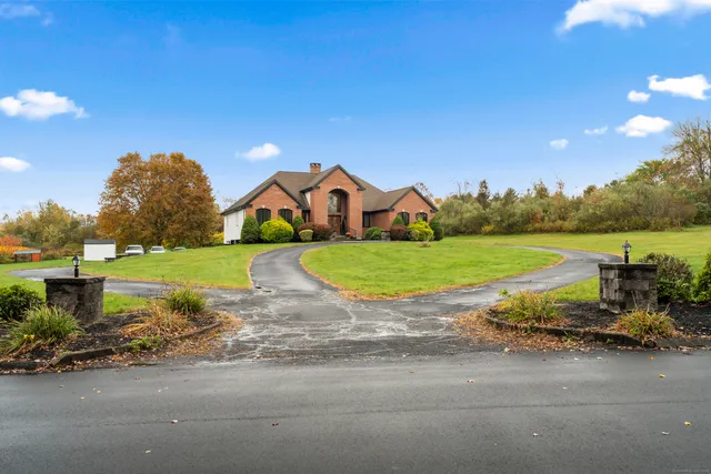 a view of a house with a big yard and large trees