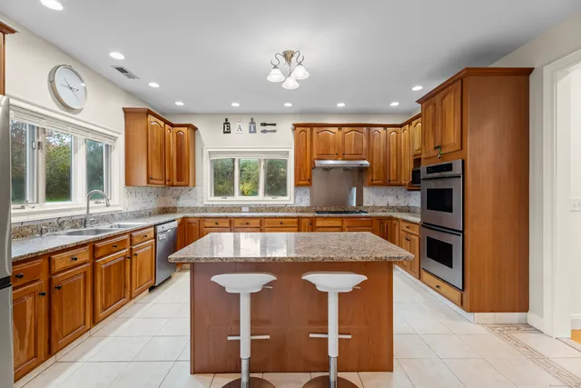a large kitchen with stainless steel appliances granite countertop a stove a sink and a microwave