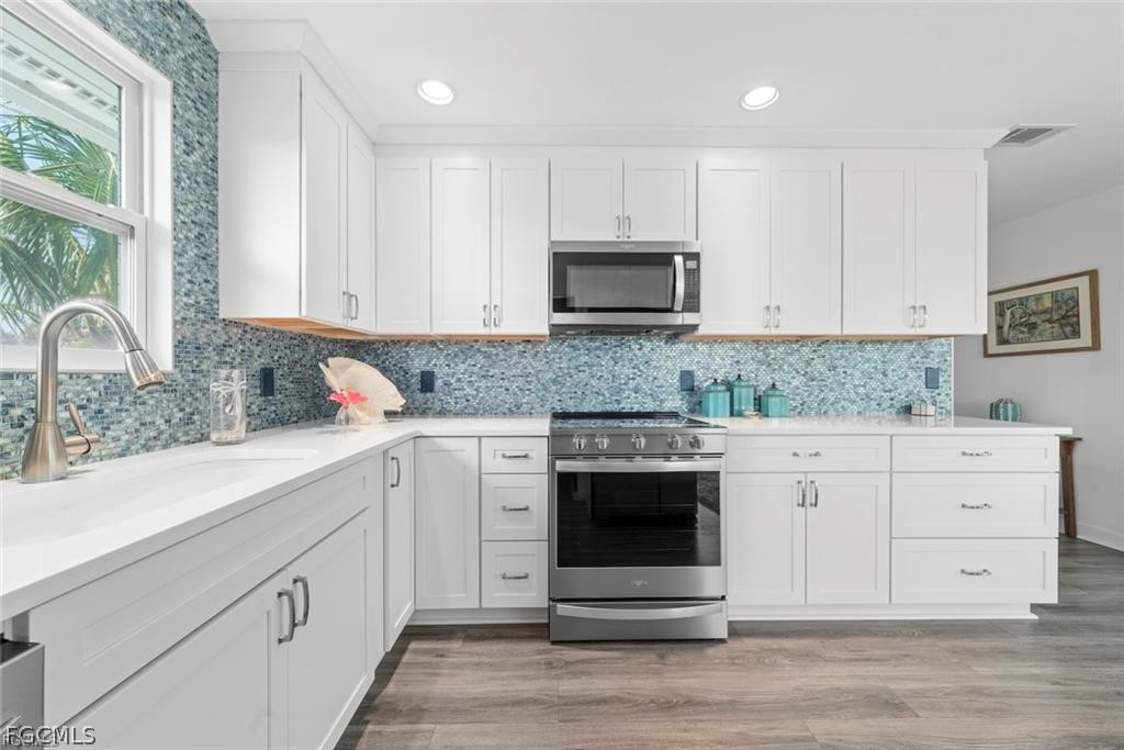6093 Henderson Road Sanibel, FL 33957 - Photo 14 of 49 a kitchen with granite countertop white cabinets stainless steel appliances and a sink