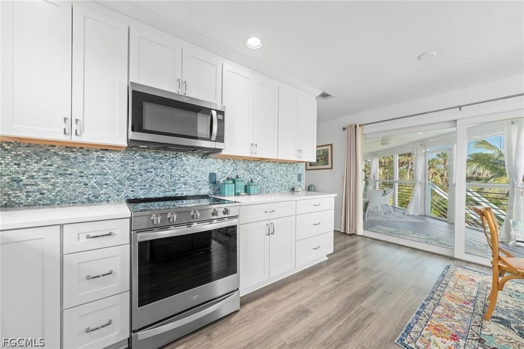 6093 Henderson Road Sanibel, FL 33957 - Photo 16 of 49 a kitchen with stainless steel appliances granite countertop a stove microwave and sink