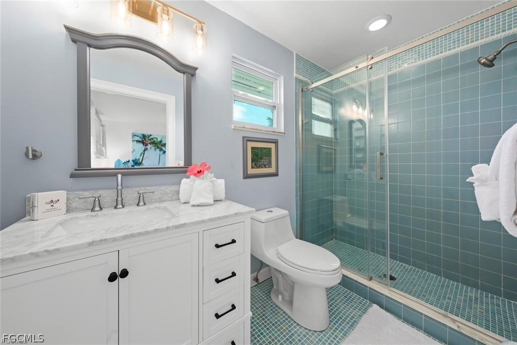 6093 Henderson Road Sanibel, FL 33957 - Photo 22 of 49 a bathroom with a granite countertop sink toilet a mirror a vanity and shower