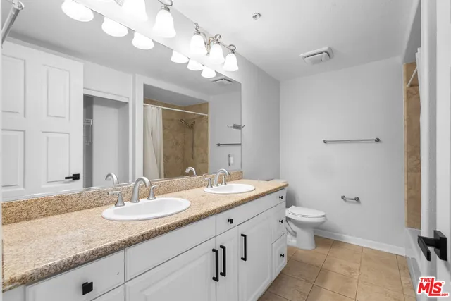 a bathroom with a granite countertop sink a toilet and a mirror