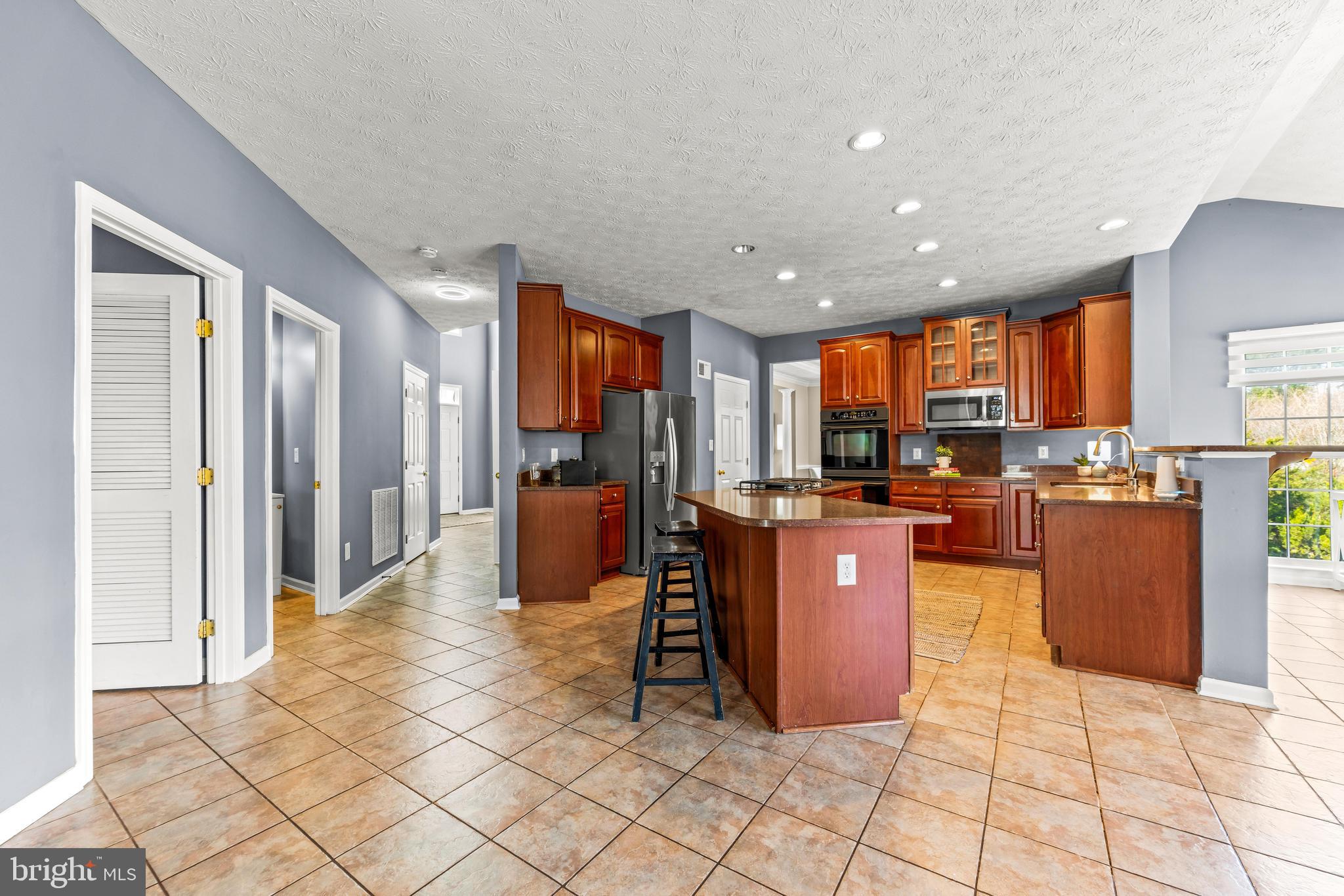 1717 Maco Drive Hanover, MD 21076 - Photo 12 of 93 a large kitchen with stainless steel appliances kitchen island granite countertop a refrigerator a oven a kitchen island and chairs in it