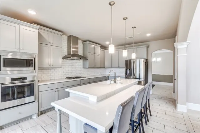 a kitchen with stainless steel appliances kitchen island granite countertop a sink a stove a refrigerator and island with wooden floor