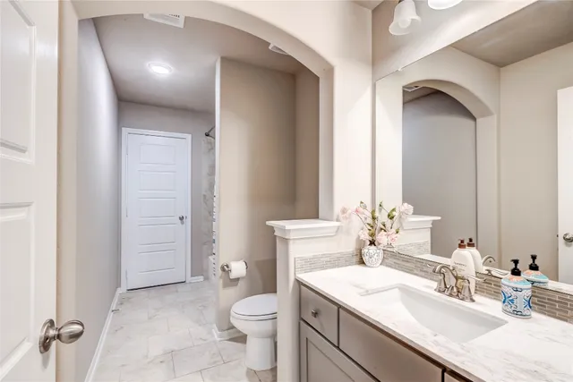 a bathroom with a granite countertop sink toilet and mirror