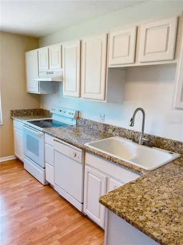 a kitchen with granite countertop white cabinets and white appliances