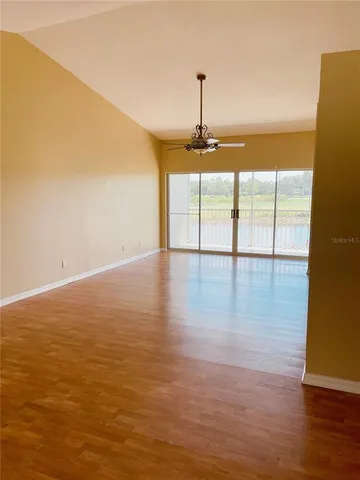 a view of empty room with wooden floor and fan