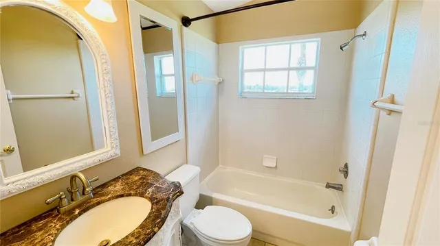a bathroom with a granite countertop sink toilet a mirror and a bathtub