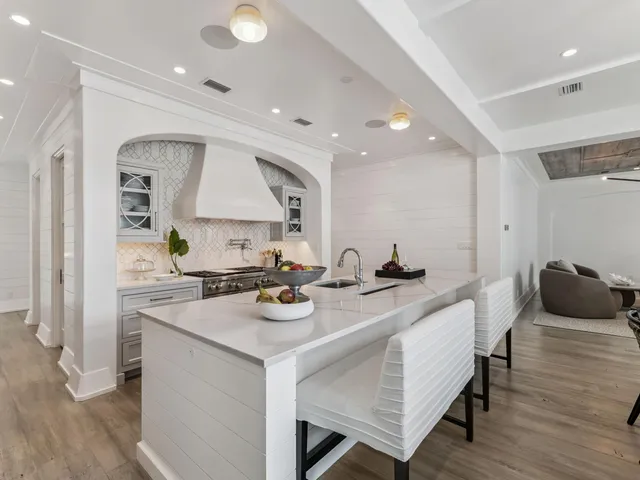 a kitchen with stainless steel appliances a stove and white cabinets with wooden floor