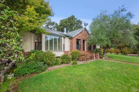 a front view of a house with a garden and trees