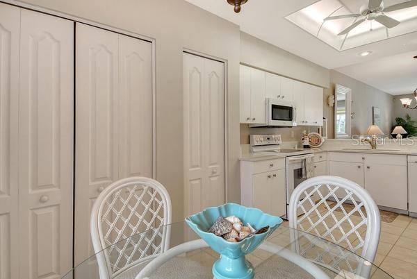 9641 Castle Point Drive, Unit 1215 Sarasota, FL 34238 - Photo 11 of 48 a kitchen with stainless steel appliances kitchen island granite countertop a refrigerator a sink dishwasher a dining table and chairs with wooden floor