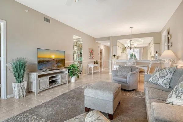 a living room with furniture a flat screen tv and a chandelier