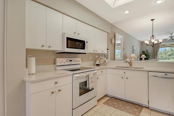 9641 Castle Point Drive, Unit 1215 Sarasota, FL 34238 - Photo 5 of 48 a kitchen with white cabinets and white appliances