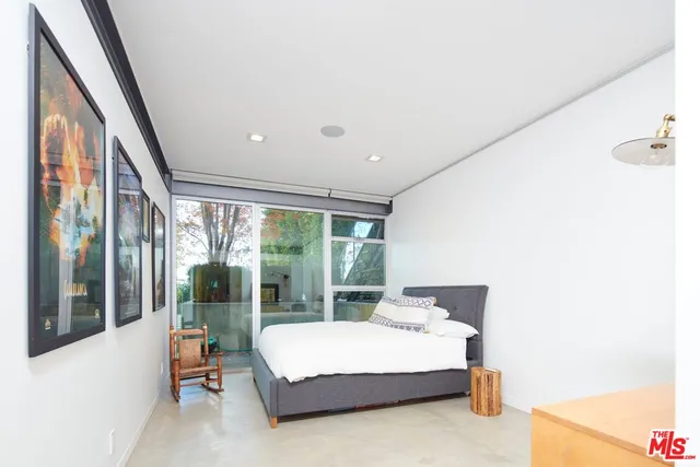 a bedroom with a bed and large windows