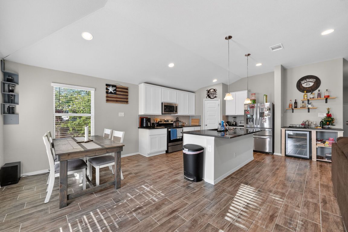 20703 Ridgeview Road Lago Vista, TX 78645 - Photo 16 of 30 a kitchen with stainless steel appliances granite countertop a refrigerator a stove top oven a sink dishwasher a dining table and chairs with wooden floor
