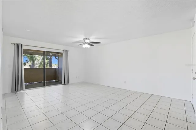 an empty space with white walls and chandelier fan