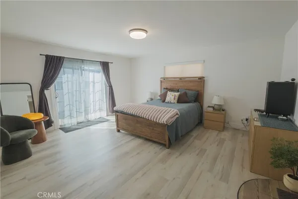 a spacious bedroom with a bed a couch and a flat tv screen on the dresser