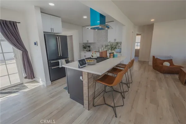 a kitchen with stainless steel appliances a dining table chairs refrigerator and sink