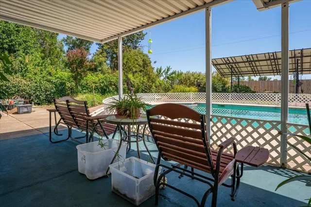 a view of a patio with table and chairs potted plants and floor to ceiling window