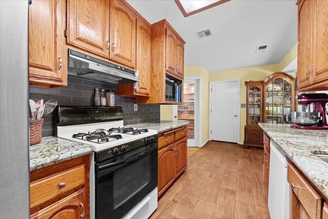a kitchen with stainless steel appliances granite countertop a stove a sink and a refrigerator