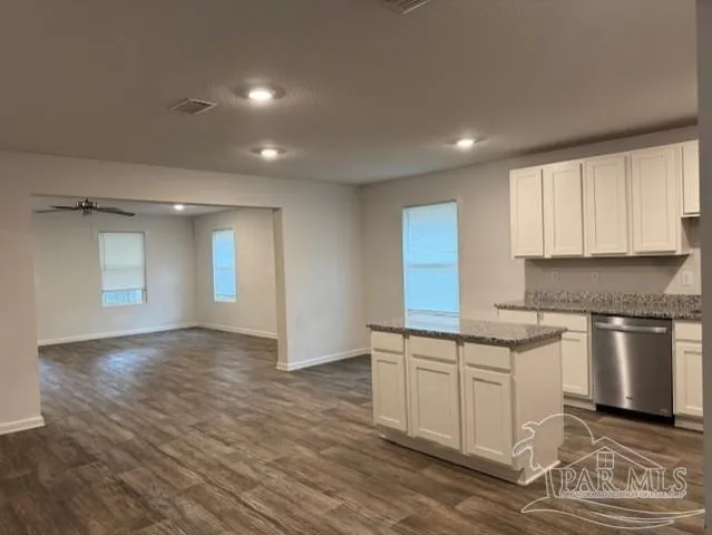 a kitchen with stainless steel appliances granite countertop a stove a sink and white cabinets with wooden floor