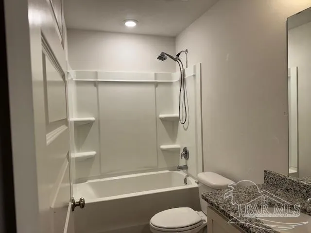 a bathroom with a granite countertop bathtub shower sink vanity and a toilet