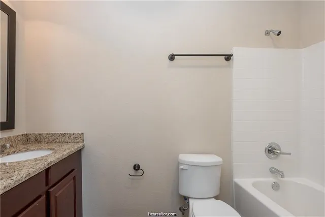 a bathroom with a granite countertop toilet a sink and a bathtub