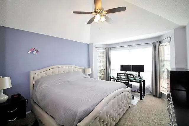 a bed sitting in a bedroom next to a window with pc on the table