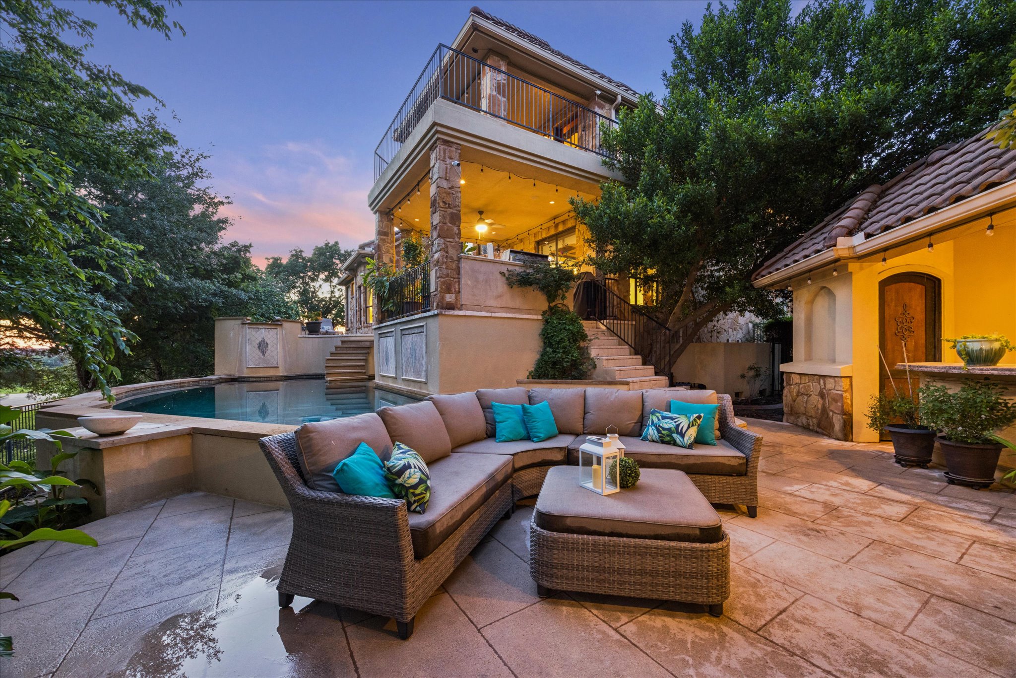 11805 Ranchview Court Austin, TX 78732 - Photo 5 of 36 Tiered stone patio with an in-ground swimming pool, stone accent walls, and a multi-level structure featuring upper and lower balconies