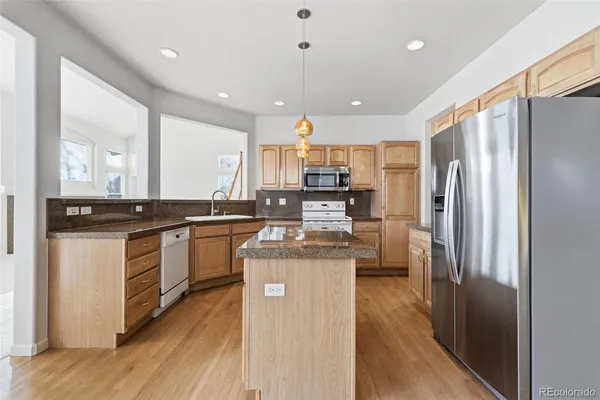 a kitchen with stainless steel appliances granite countertop a refrigerator a stove and a sink