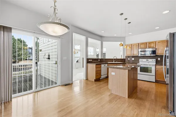 a kitchen with stainless steel appliances granite countertop a refrigerator a sink a stove a microwave and island with wooden floor