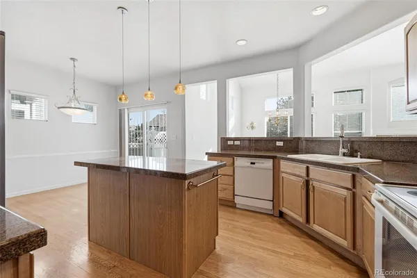 a kitchen with stainless steel appliances granite countertop a sink a stove and a wooden floors