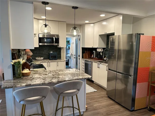 a kitchen with stainless steel appliances granite countertop a sink refrigerator and cabinets