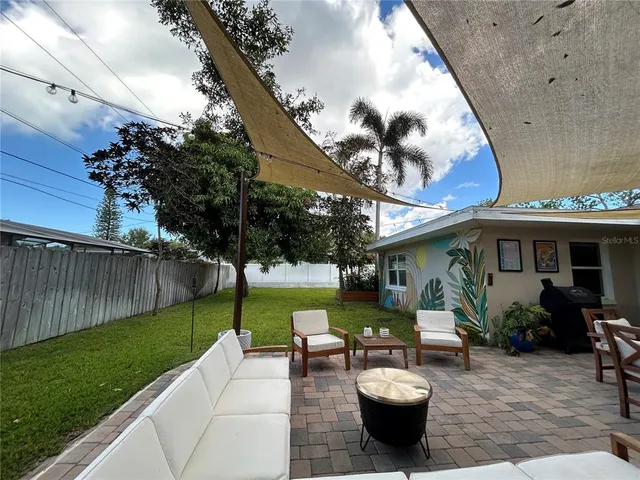 a view of a backyard with table and chairs potted plants and a palm tree