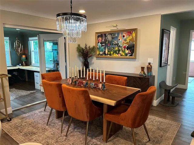 a dining room with furniture a rug a potted plant and a chandelier