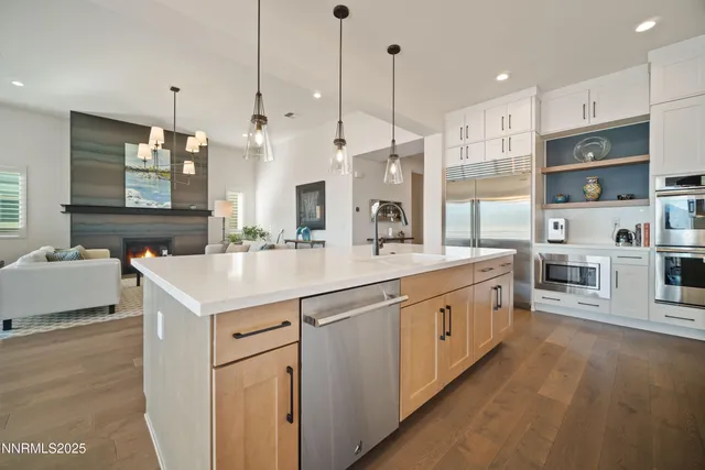 a kitchen with stainless steel appliances kitchen island granite countertop a table chairs and a sink