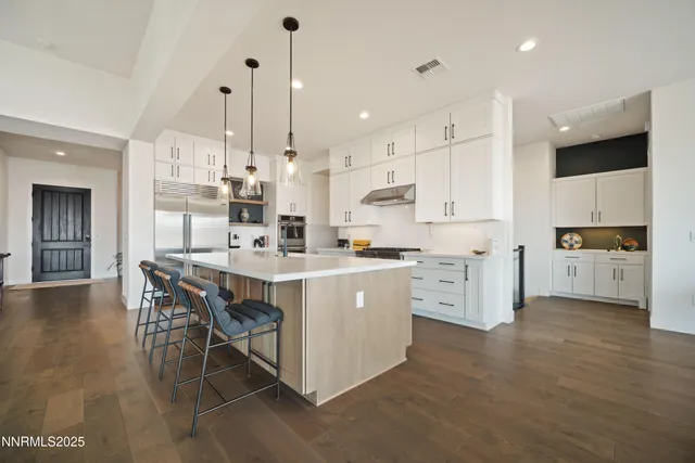 a kitchen with stainless steel appliances granite countertop a refrigerator oven a stove and white cabinets with wooden floor