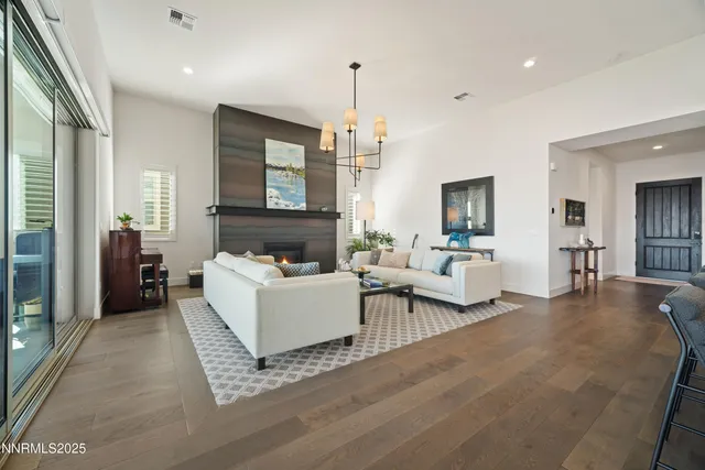 a kitchen with stainless steel appliances granite countertop a sink a stove a refrigerator and chairs with wooden floor