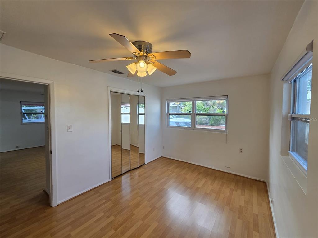 7216 James Street Port Richey, FL 34668 - Photo 16 of 28 an empty room with wooden floor chandelier fan and windows