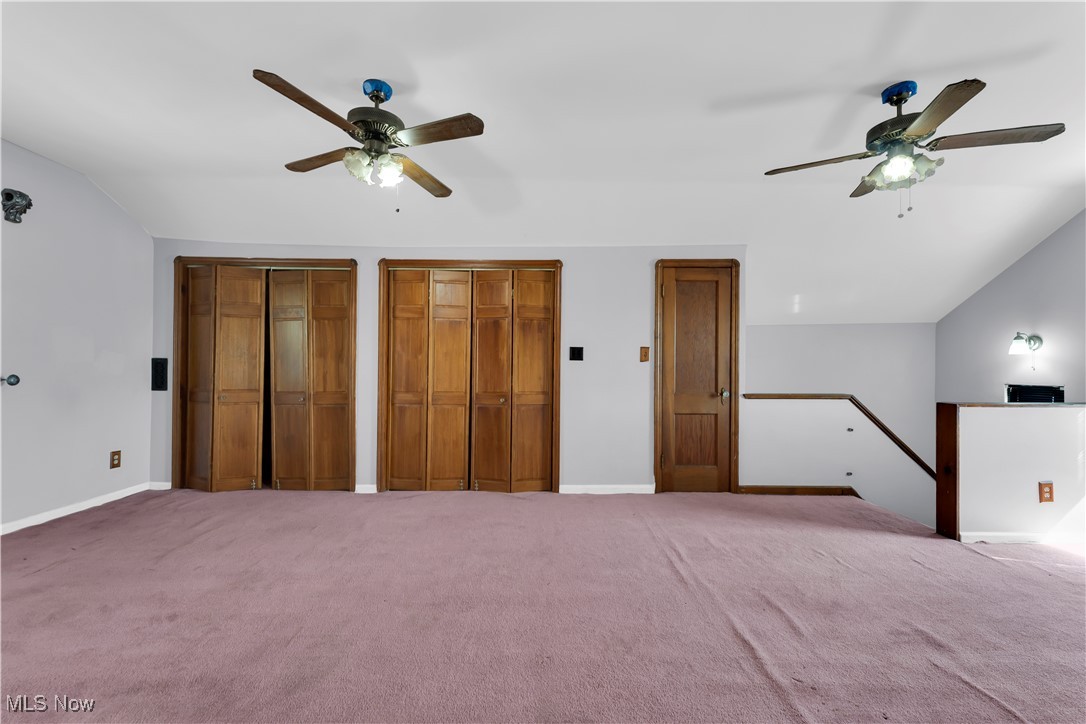 3739 Warren Road Cleveland, OH 44111 - Photo 25 of 40 Unfurnished bedroom with multiple closets, a ceiling fan, carpet, and lofted ceiling