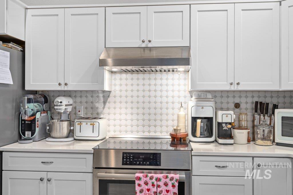 6697 West Irish Circle Rathdrum, ID 83858 - Photo 10 of 36 Kitchen featuring appliances with stainless steel finishes, under cabinet range hood, white cabinetry, and light stone counters