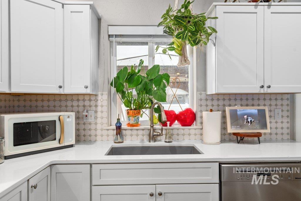 6697 West Irish Circle Rathdrum, ID 83858 - Photo 11 of 36 Kitchen featuring white microwave, dishwasher, white cabinets, and light stone counters