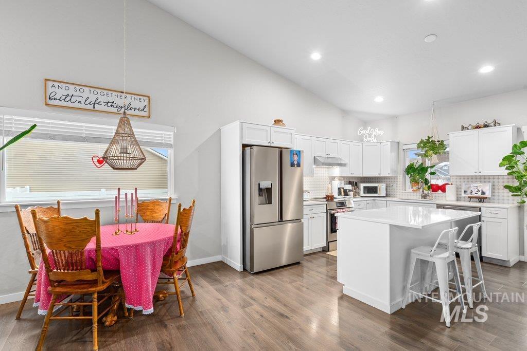 6697 West Irish Circle Rathdrum, ID 83858 - Photo 12 of 36 Kitchen featuring stainless steel appliances, a kitchen breakfast bar, white cabinetry, a kitchen island, and tasteful backsplash