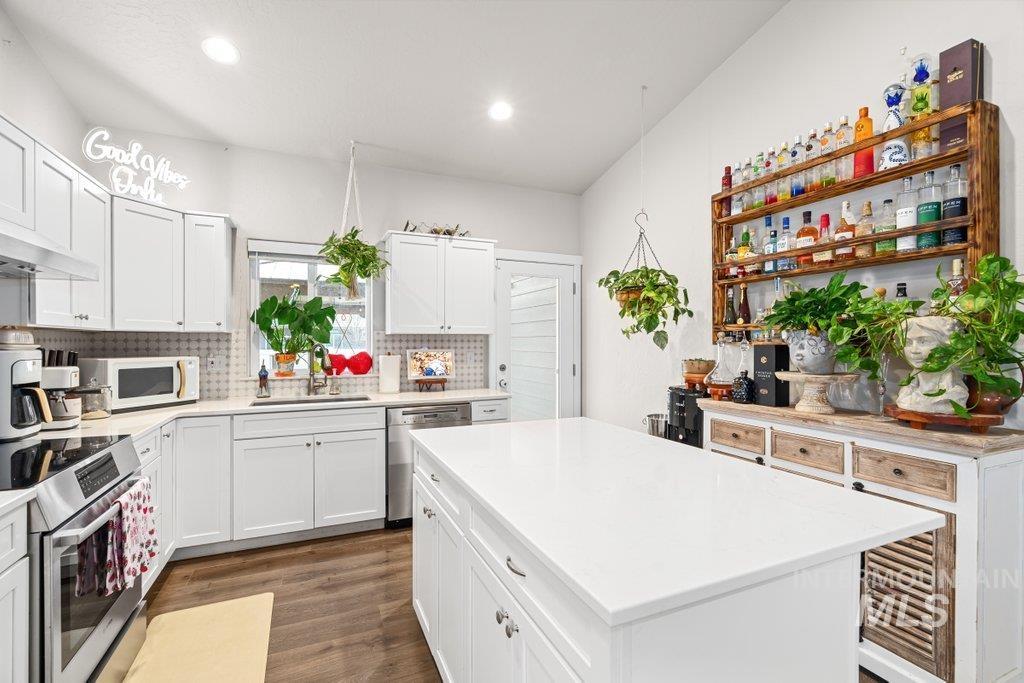 6697 West Irish Circle Rathdrum, ID 83858 - Photo 8 of 36 Kitchen with stainless steel appliances, white cabinets, dark wood finished floors, tasteful backsplash, and a kitchen island