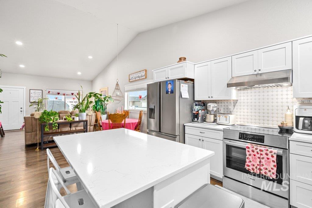 6697 West Irish Circle Rathdrum, ID 83858 - Photo 9 of 36 Kitchen featuring stainless steel appliances, a kitchen island, white cabinets, pendant lighting, and under cabinet range hood