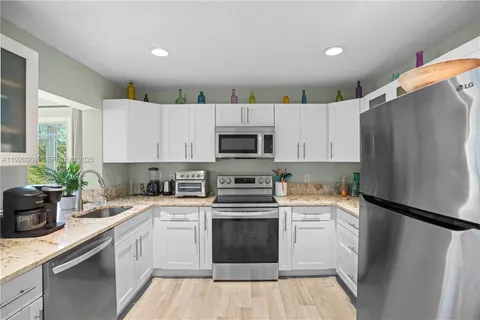 a kitchen with white cabinets white stainless steel appliances and a refrigerator